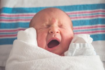 Swaddled baby yawning