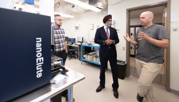 Dr. Leonard Foster shows federal Minister Harjit Sajjan how his lab is working to improve the delivery technology behind mRNA vaccines.