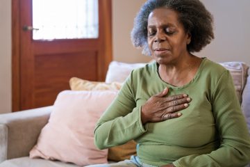 Image of elderly woman having chest pain in living room.
