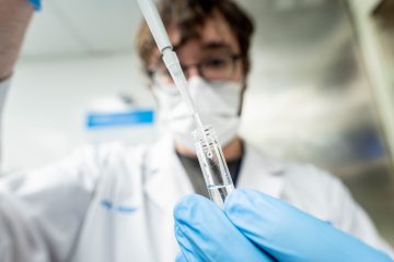 A scientist pipettes components of a radiopharmaceutical drug.