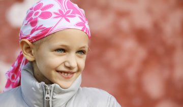 A young girl wearing a head scarf due to hair loss from chemotherapy fighting cancer.