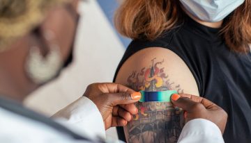 A health care provider places a bandage on the injection site of a patient, who just received a vaccine.