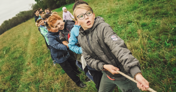 A group of children playing tug of war outside.