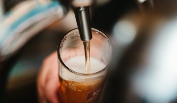 Person filling clear glass with liquid.