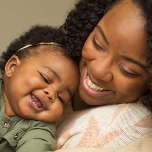 A smiling mother holding their baby in their arms.