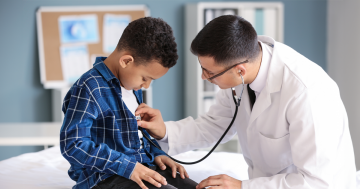 Pediatrician examining African-American boy in clinic