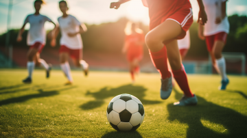 A close up of kids playing soccer on a field outdoors.