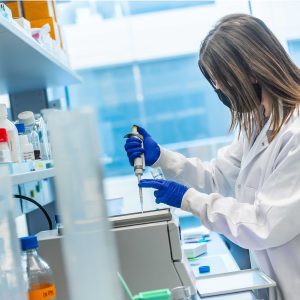 A researcher in a lab coat using a pipette at a lab bench.