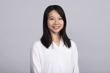 Dr. Miini Teng smiling at camera with grey background.